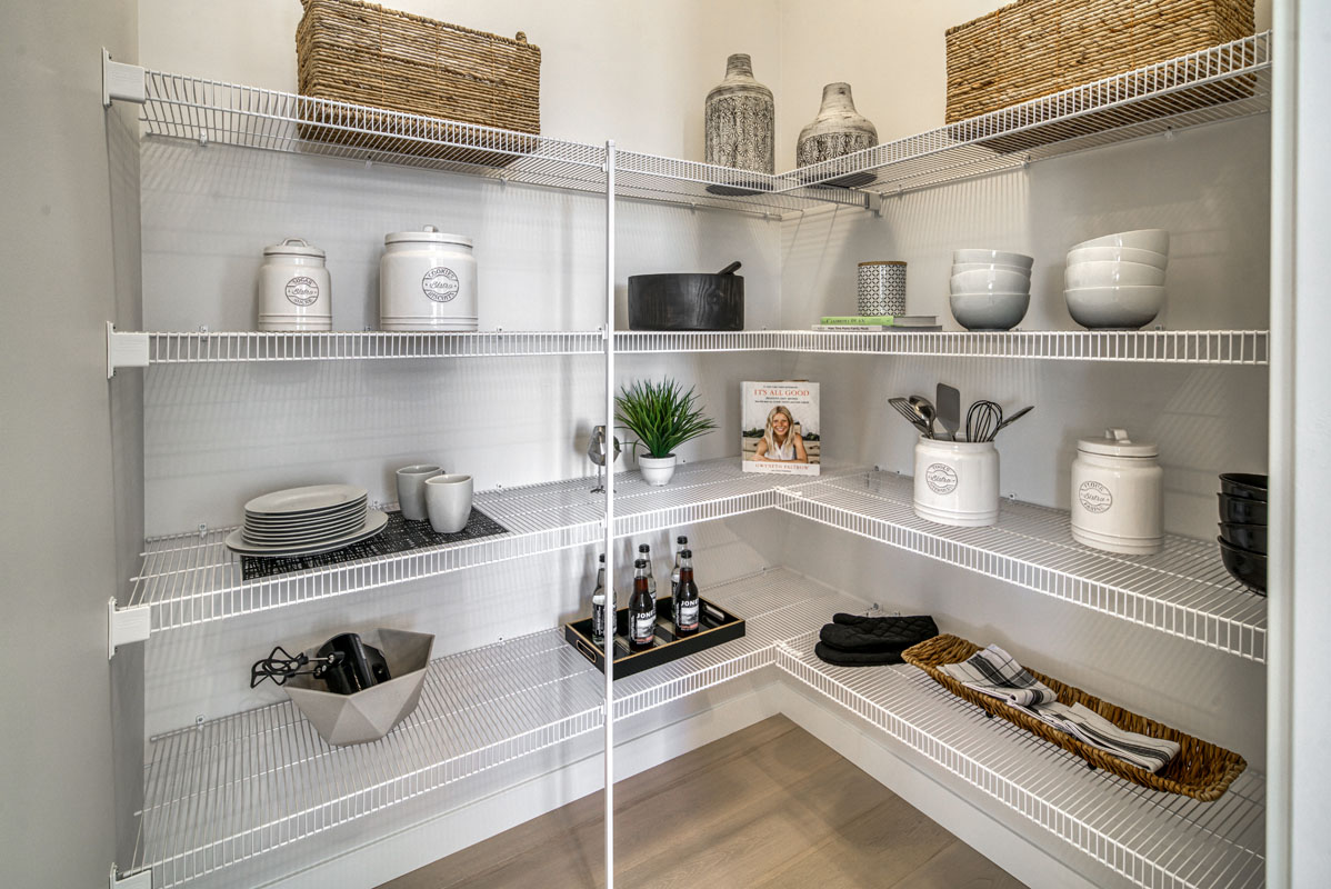 Pantry with corner white shelving and kitchen supplies in the Lakeview model home.