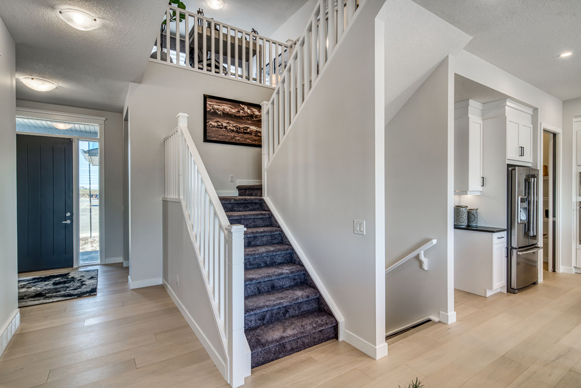 Main stair case with dark grey carpet and white hand rails in the Lakeview model home.