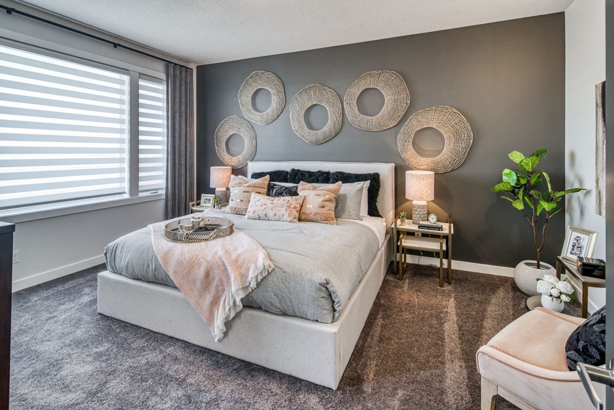 Master bedroom with matching nightstands and white plush chair in the Lakeview model home.