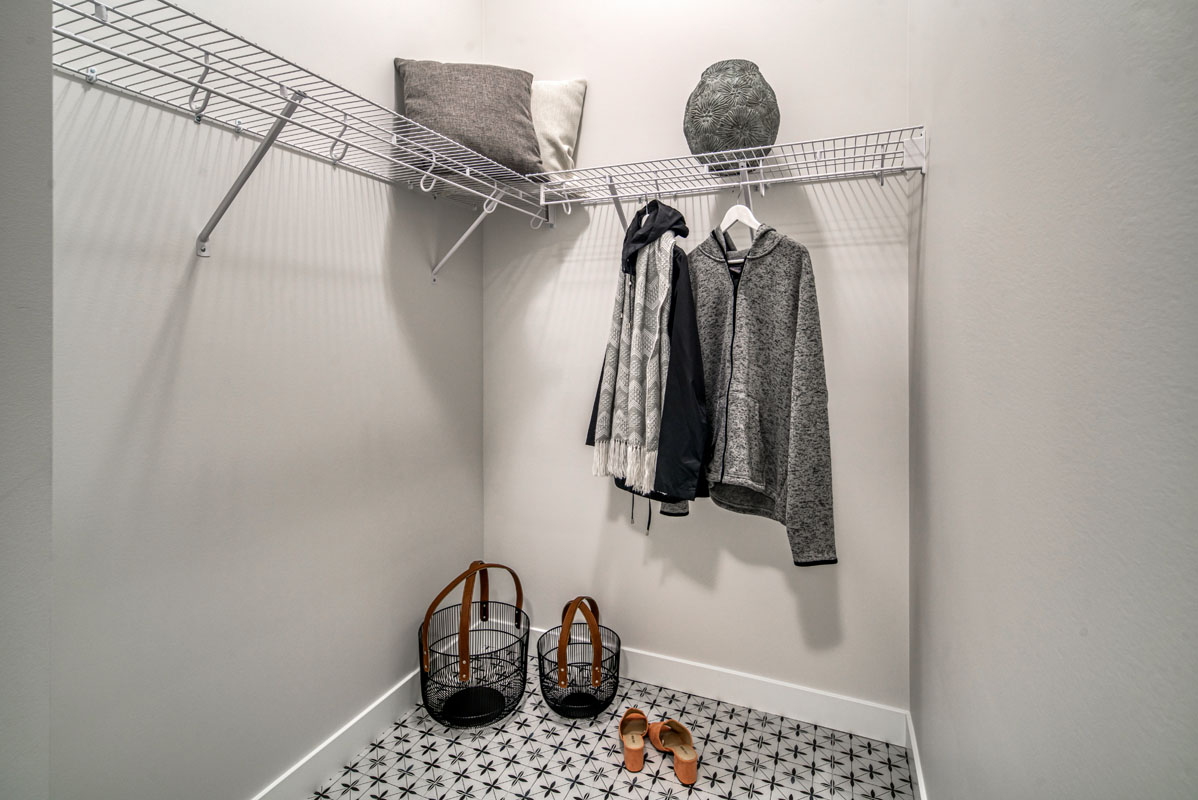 Mudroom closet with jackets hanging up and shoes on the floor in the Lakeview model home.