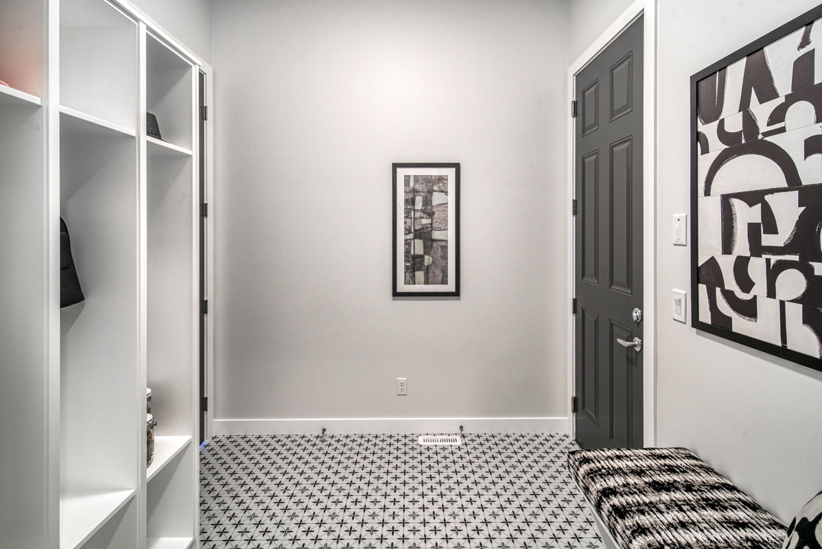 Mudroom with large white cupboards and black and white print flooring in the Lakeview model home.