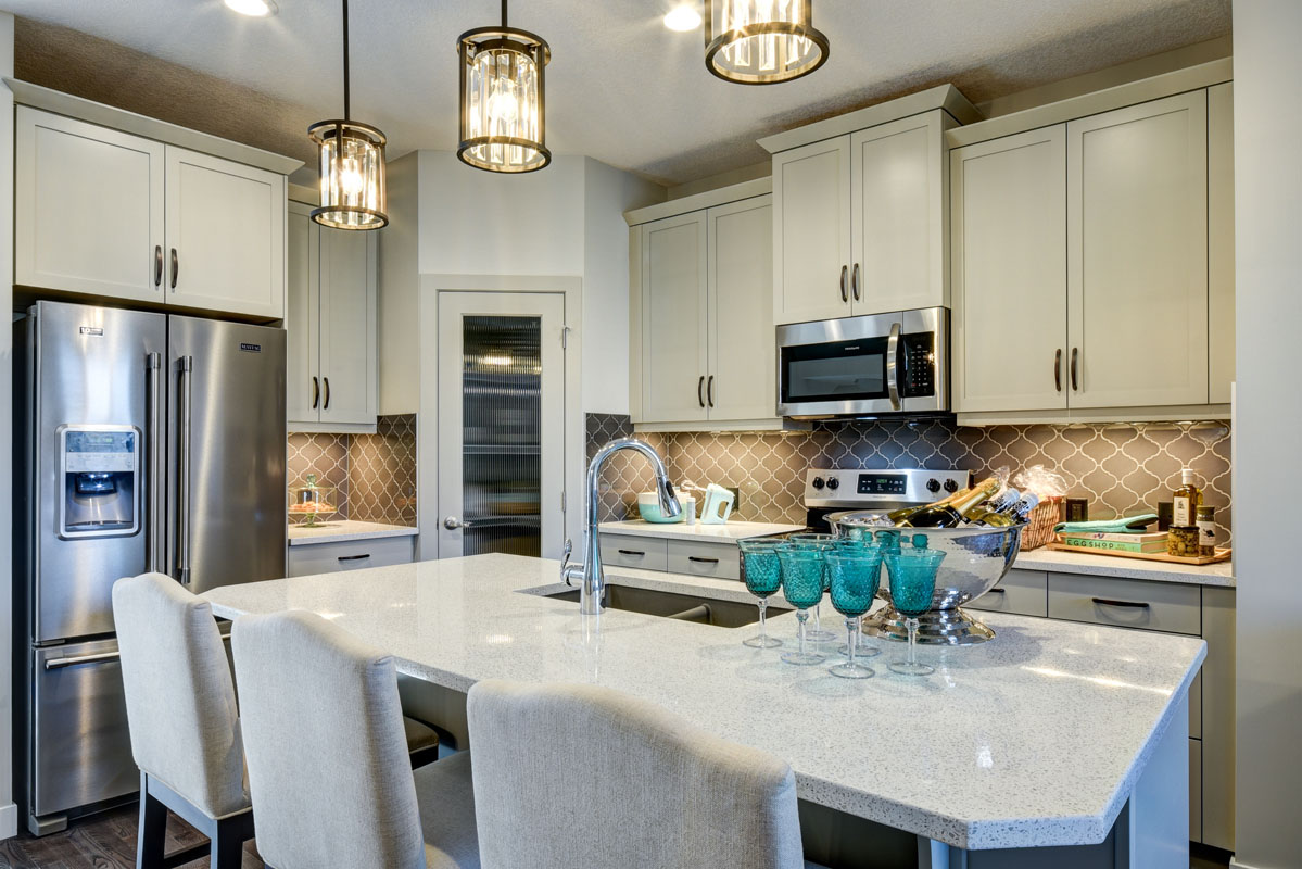 Kitchen with large marble island across from matching stainless steel appliances in the NuHaven II model home.