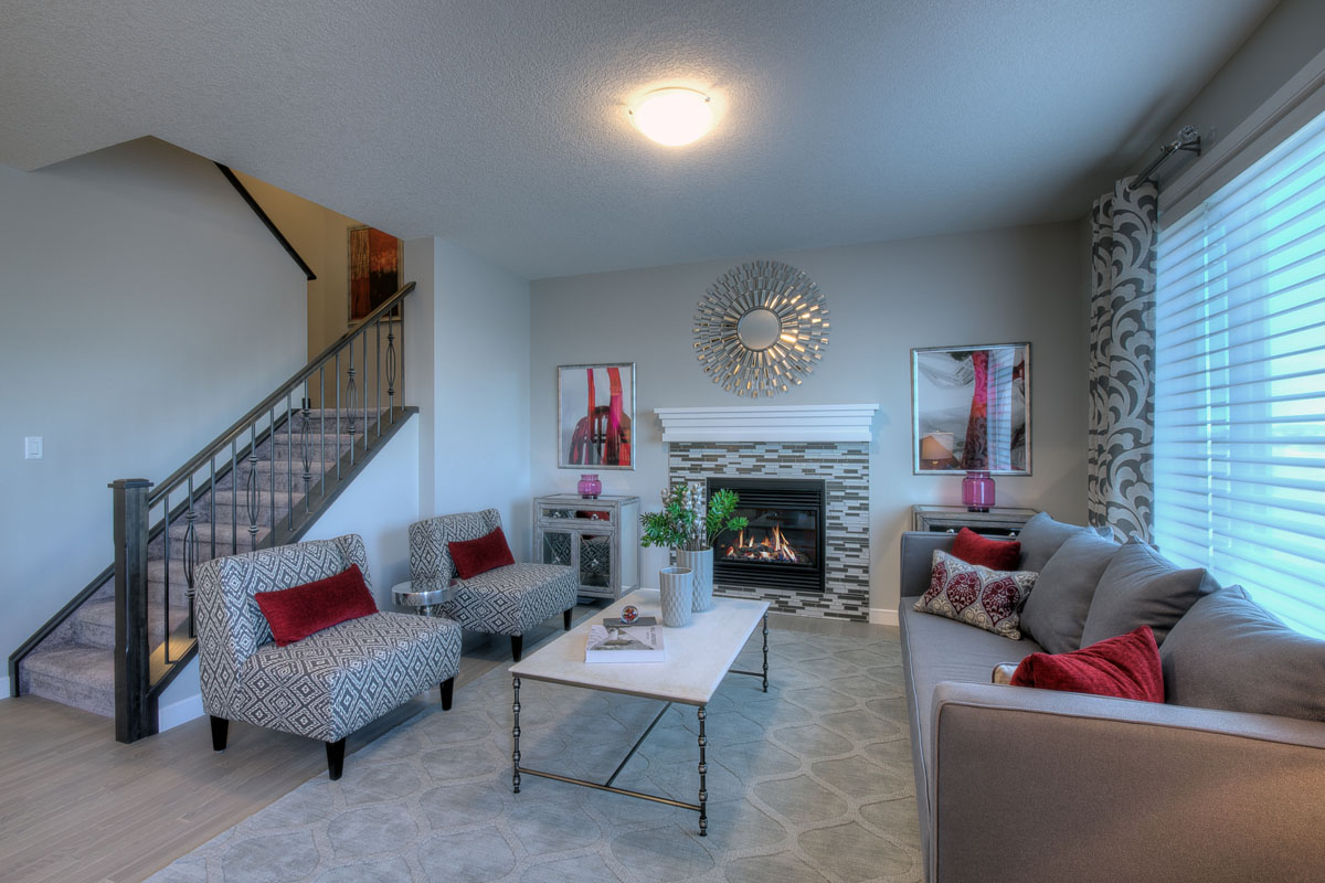 Living room with fire place and two matching chairs across from grey couch in the Riverton model home.