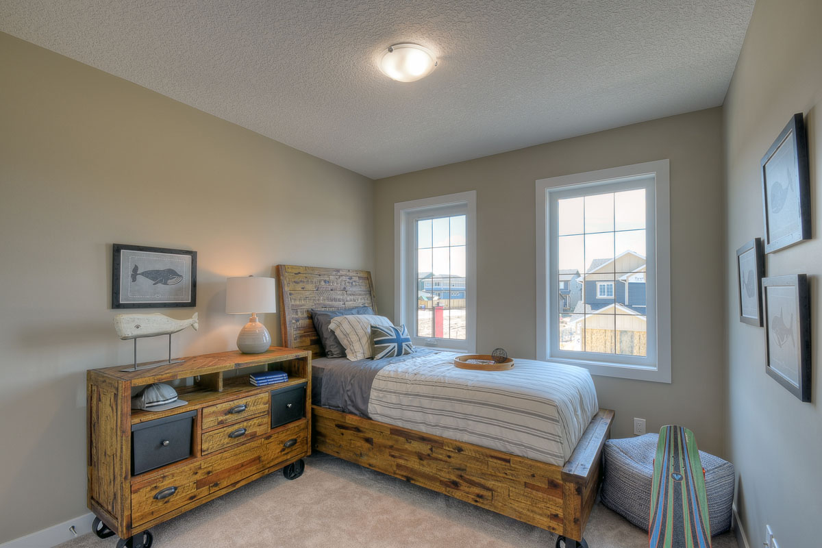 Bedroom two with twn bed on rustic wood frame next to windows and rustic wood dresser in the Rosewood model home.