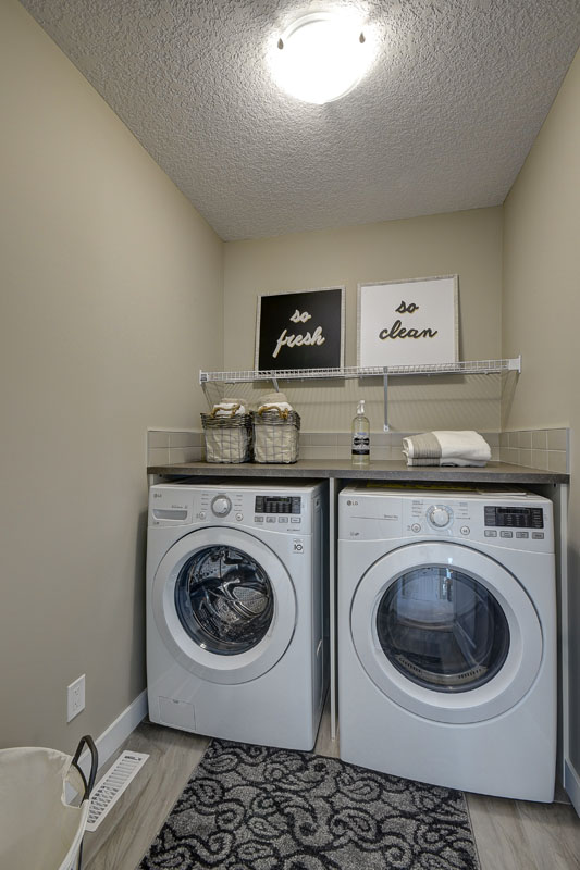 Laundry room with matching white LG washing machines and "so fresh" "so clean" pictures on the wall in the Rosewood model home.