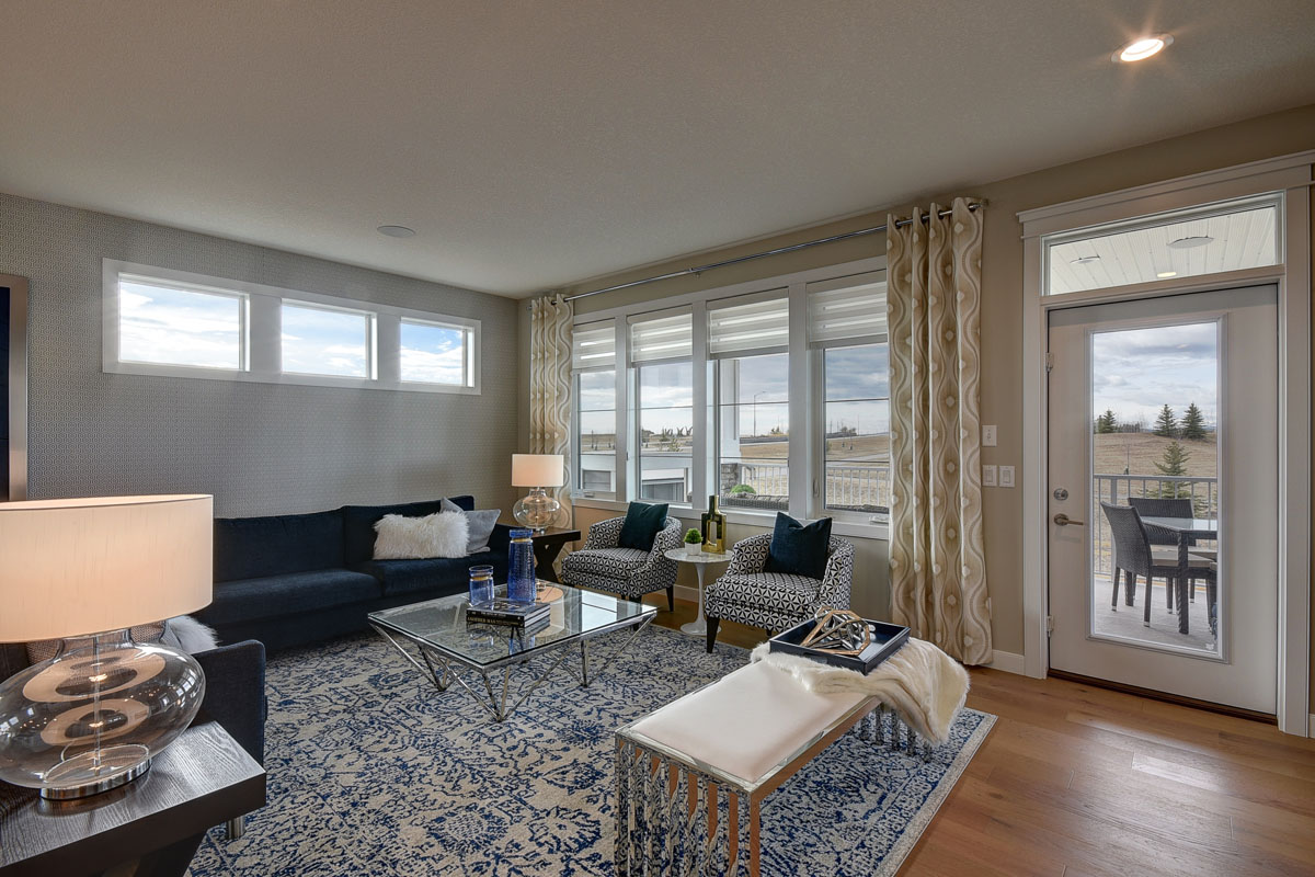 Living room with large white and blue print area rug and blue sectional in the Cayenne model home.