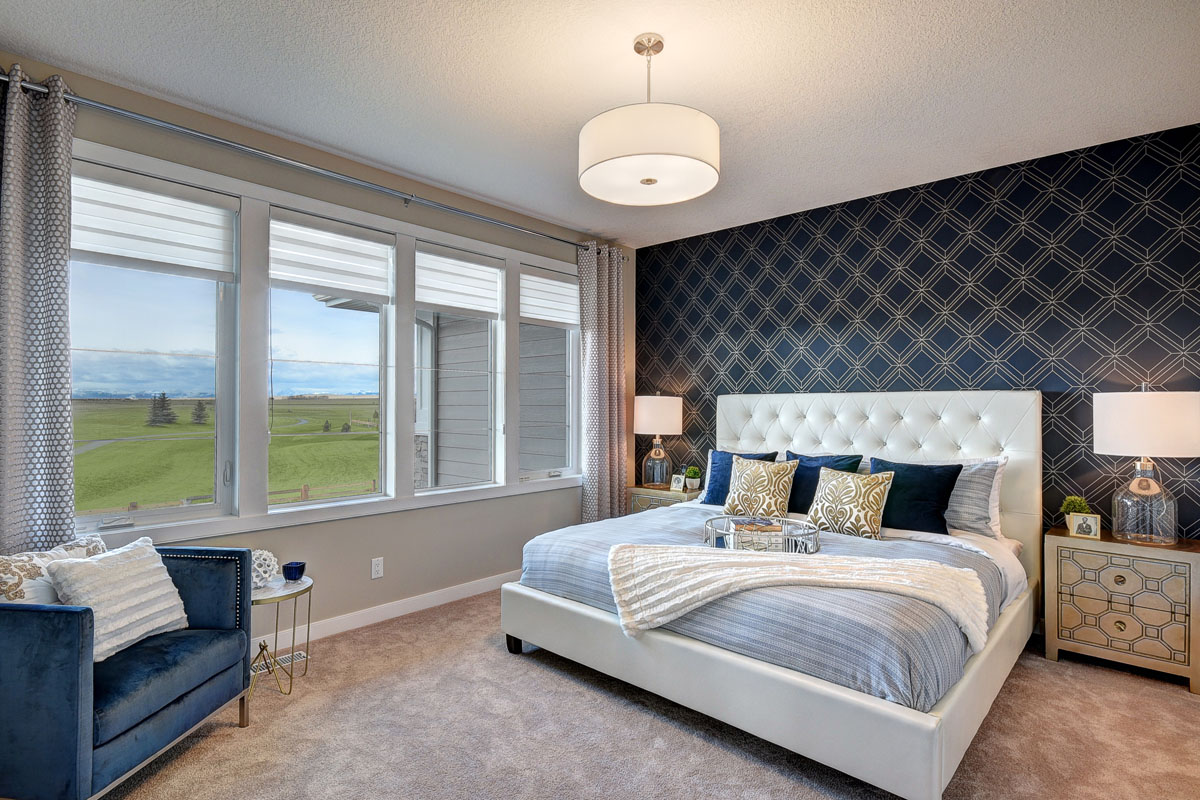 Large master bedroom with bay windows and a navy and gold diamond accent wall in the Cayenne model home.