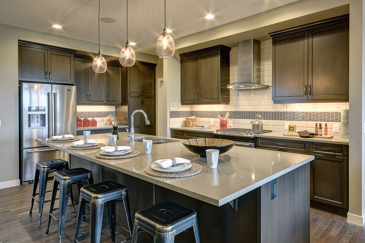 Kitchen facing the large island with grey granite counter tops and four steel barstools in the Saffron model home.