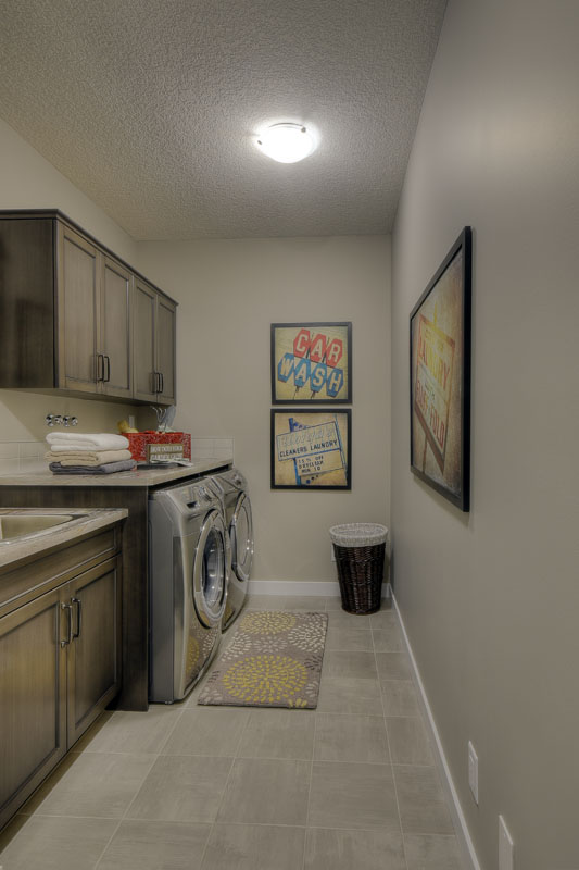 Laundry room with matching silver washer and dryer with sink and countertop in the Saffron model home.