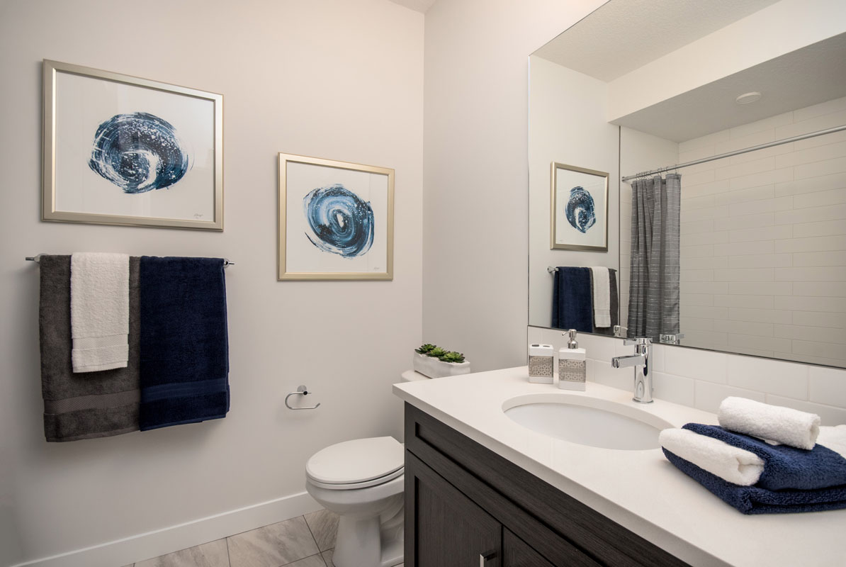 Basement bathroom with large brown and white vanity beside toliet across from the shower in the Wilshire model home.