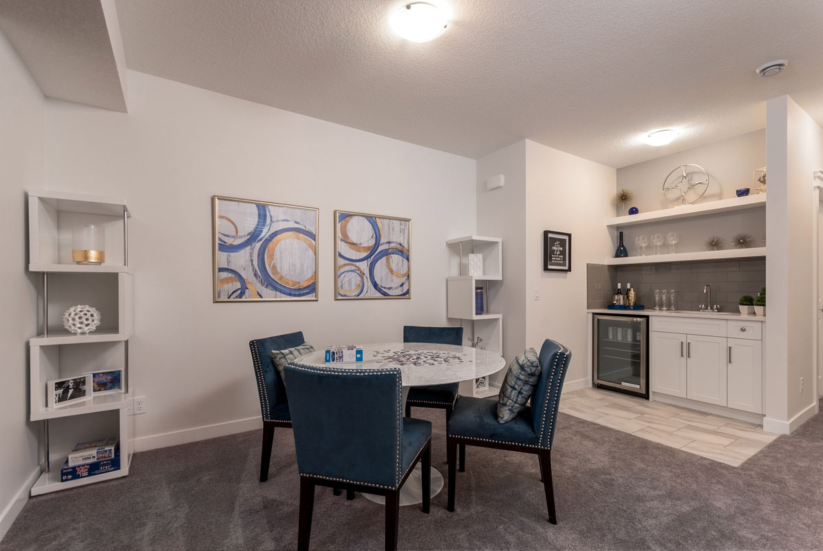 Basement wet bar area with round retro white table and four matching blue chairs in the Wilshire model home.