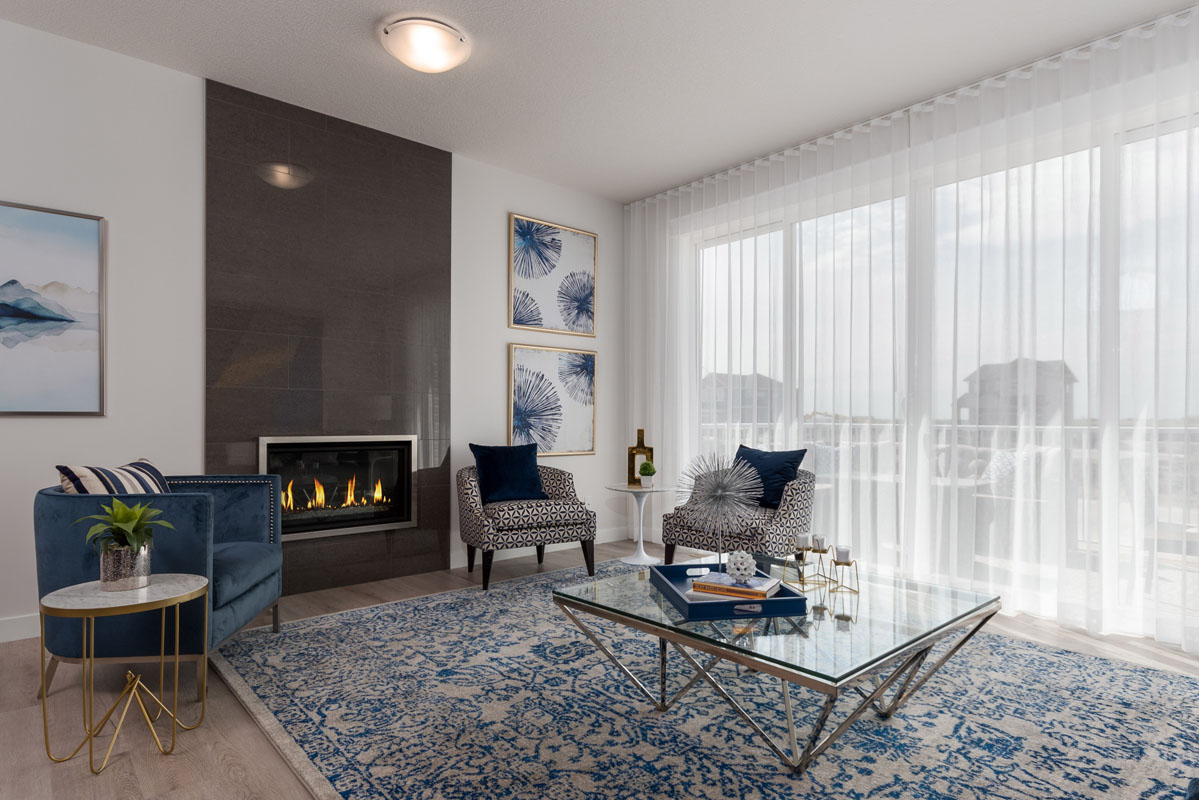 Living room with large white and blue print rug and three chairs next to glass table in the Wilshire model home.