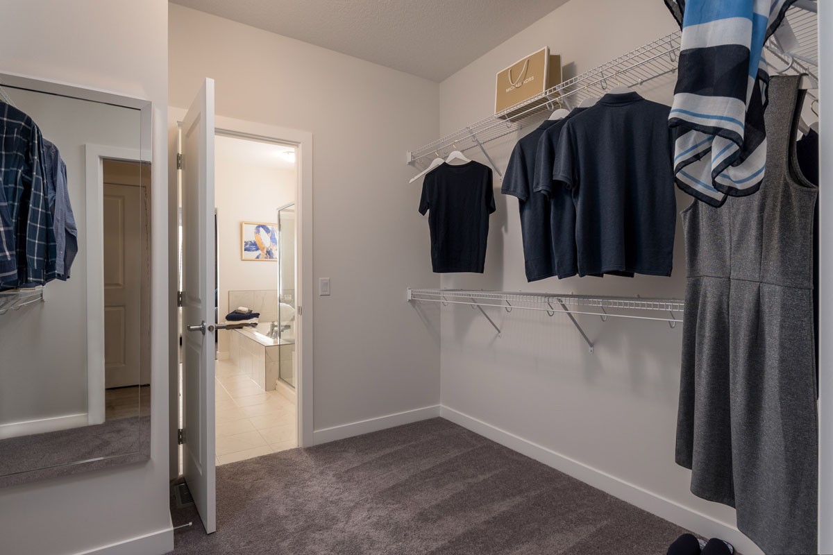 Large walk in closet in the Wilshire model home with two level shelving and clothes hanging up.